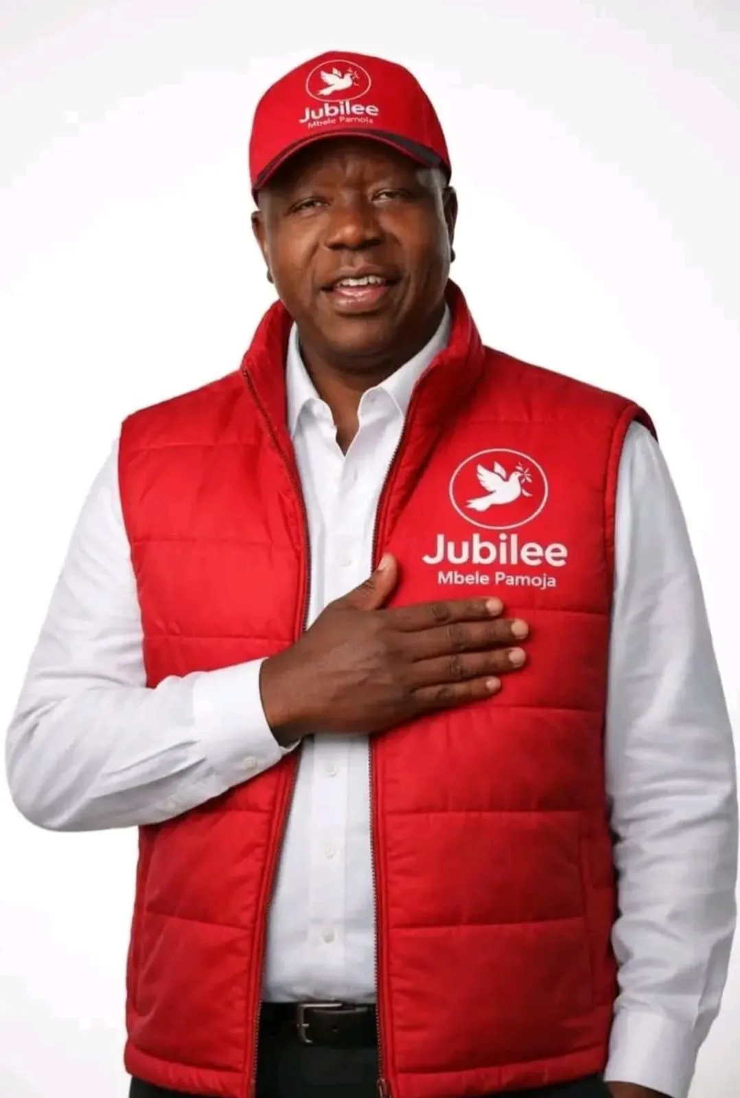 Dr Fred Matiang'i in a red vest and cap with his hand on his heart