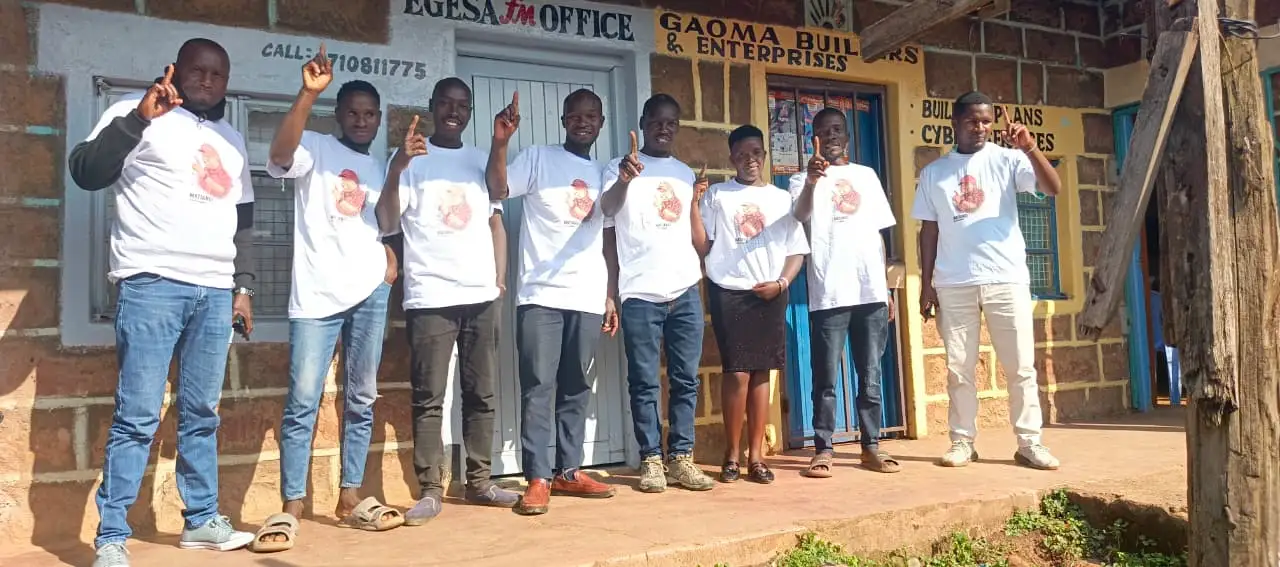 Team in white tees outside a ward office
